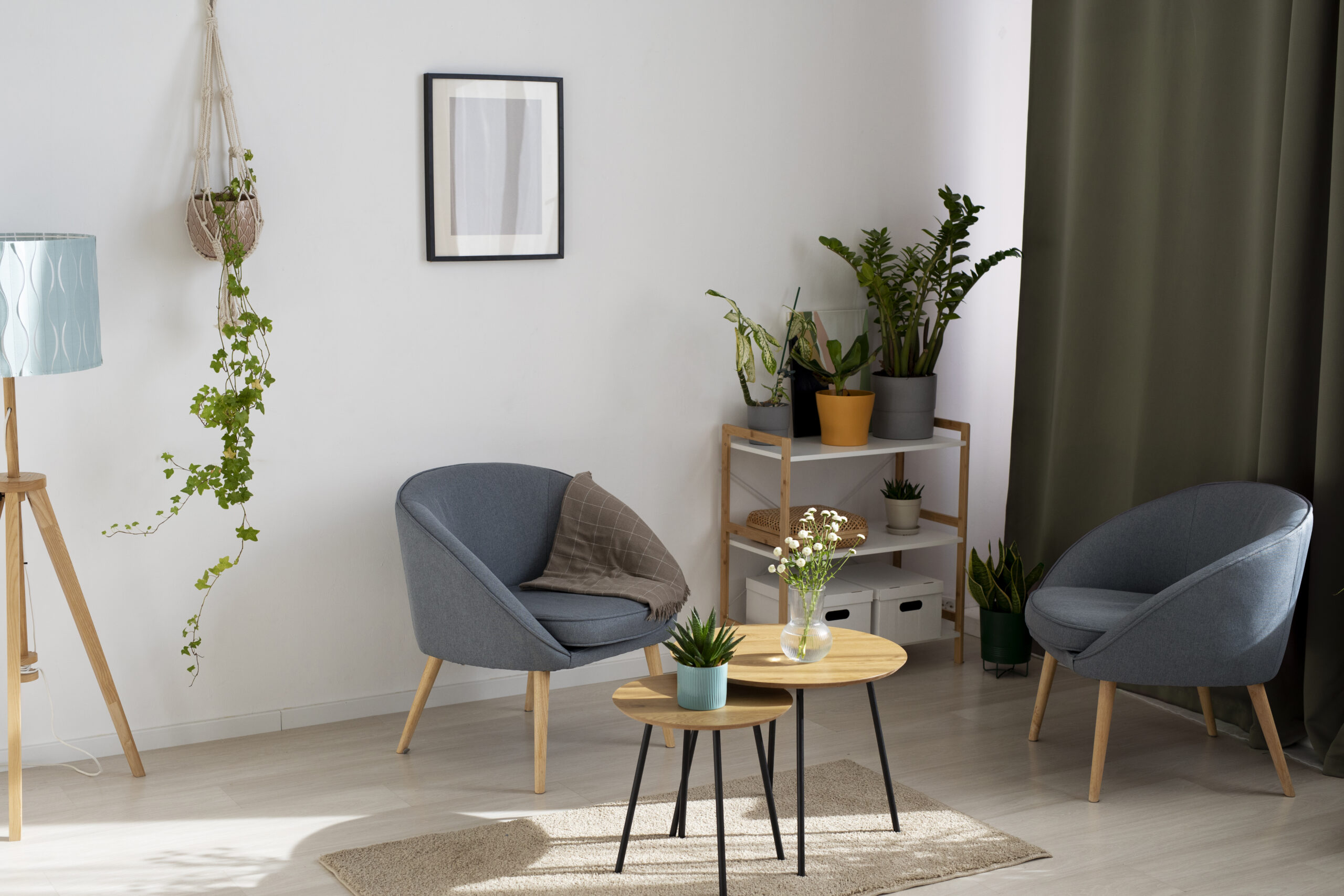 Een woonkamer met stoelen en klein bijzettafeltje planten en een gordijn.