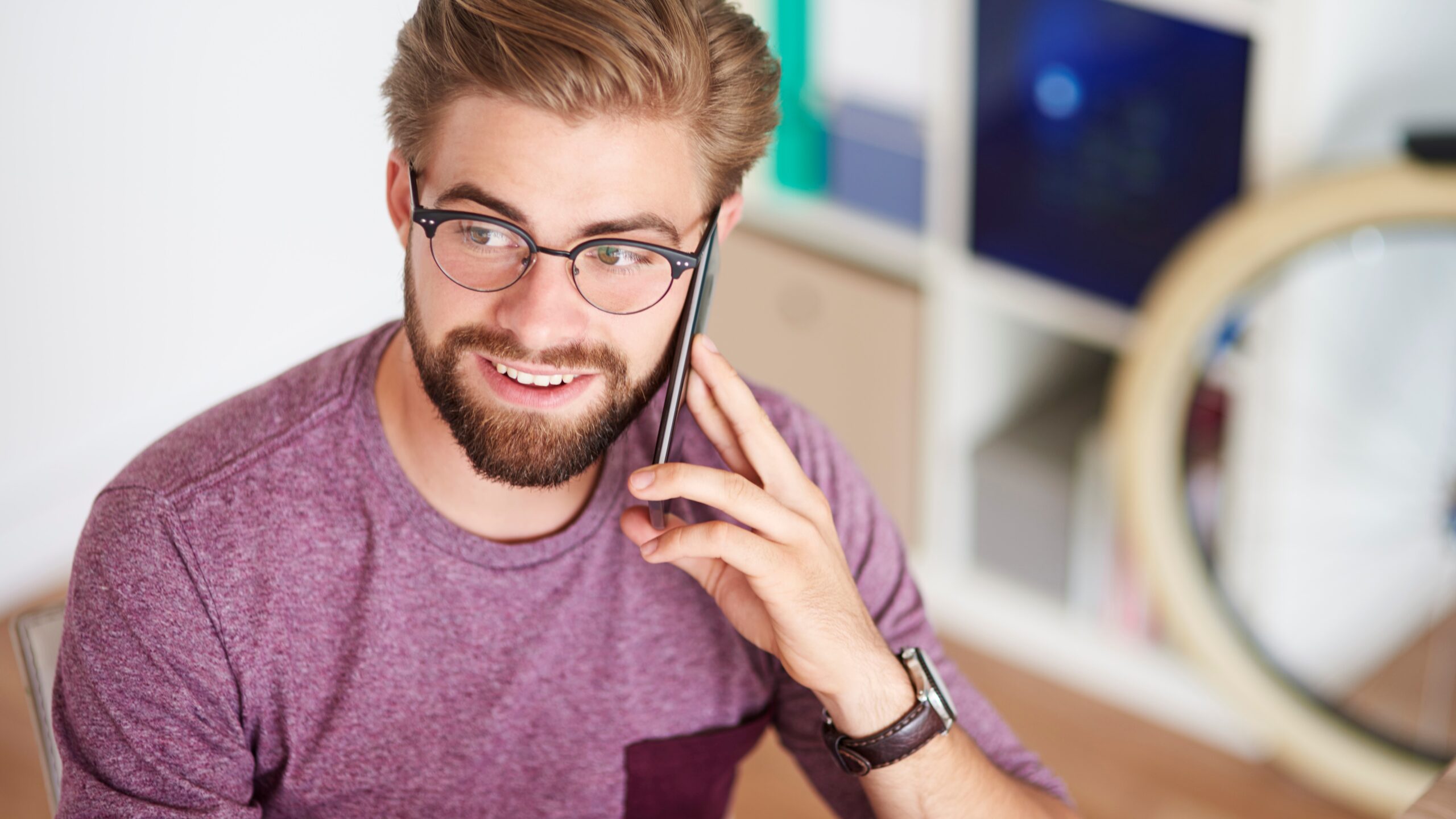 Man met bril en baard aan de telefoon