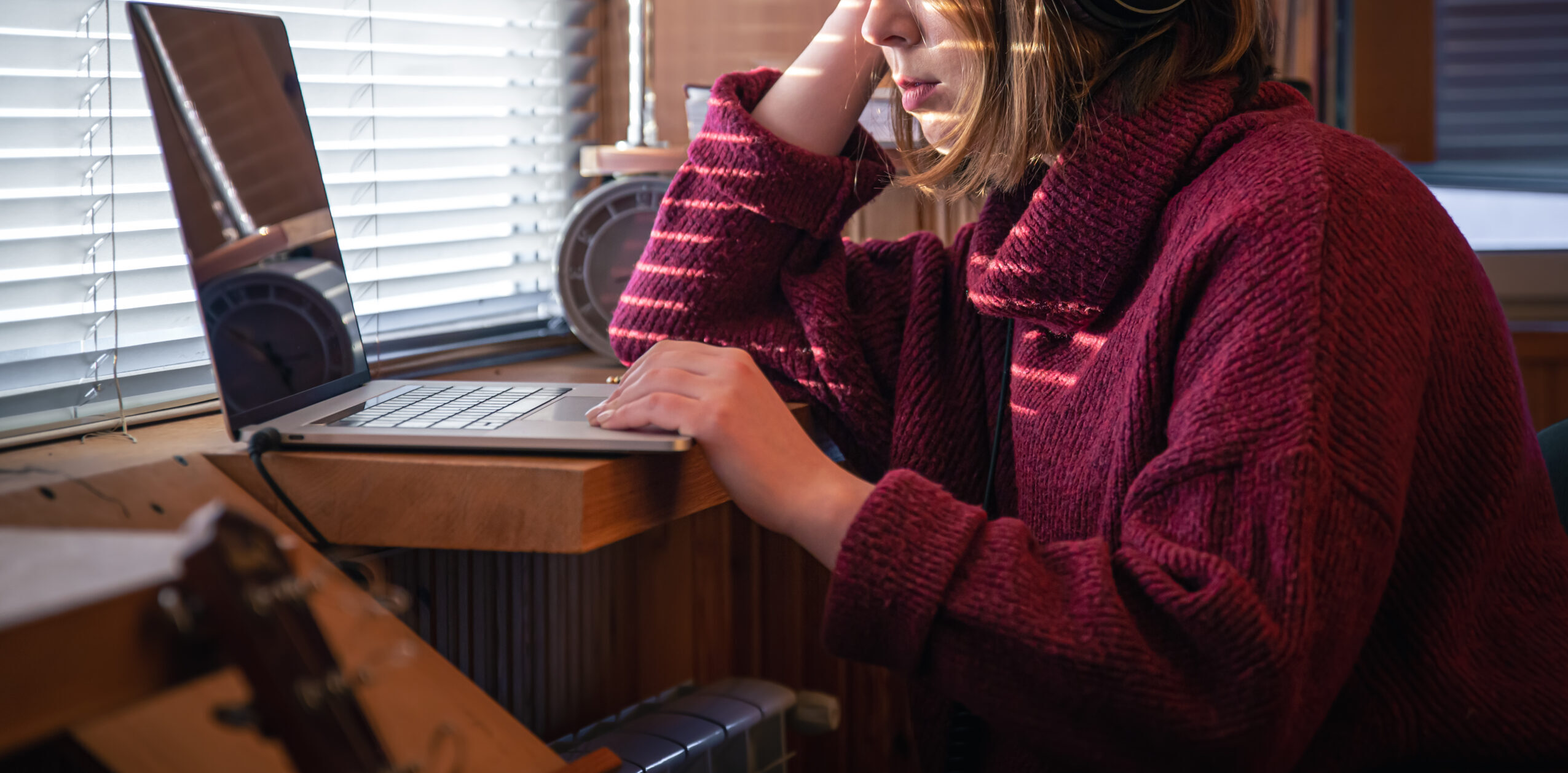 Een vrouw zit achter de laptop, je kunt haar ogen niet zien.