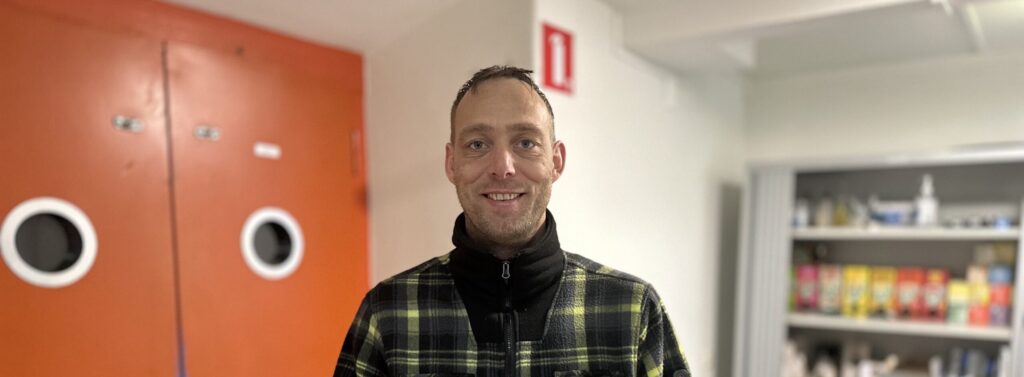 Jongeman met geruit overhemd voor de lift en kast.